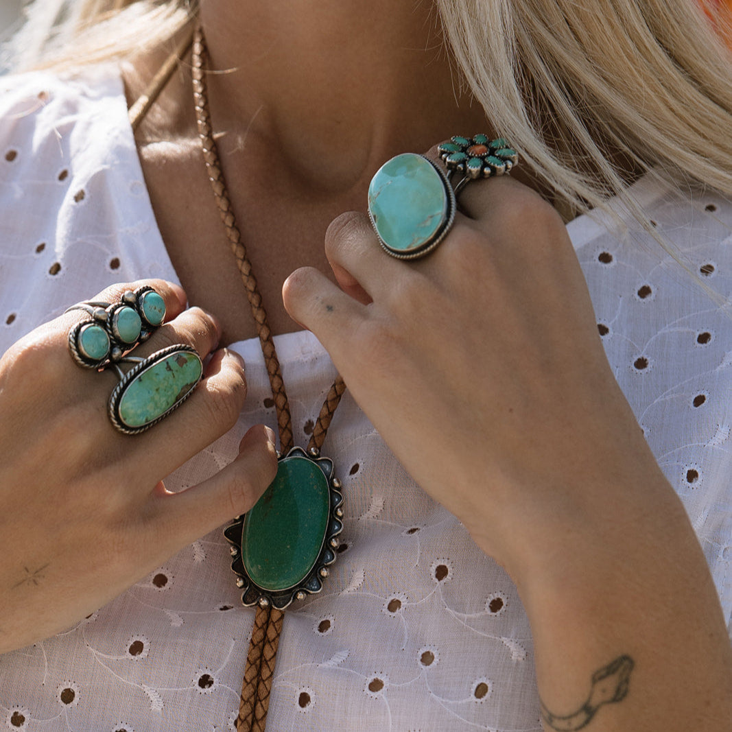 Close-up of turquoise jewelry on a person wearing a white polka dot top.