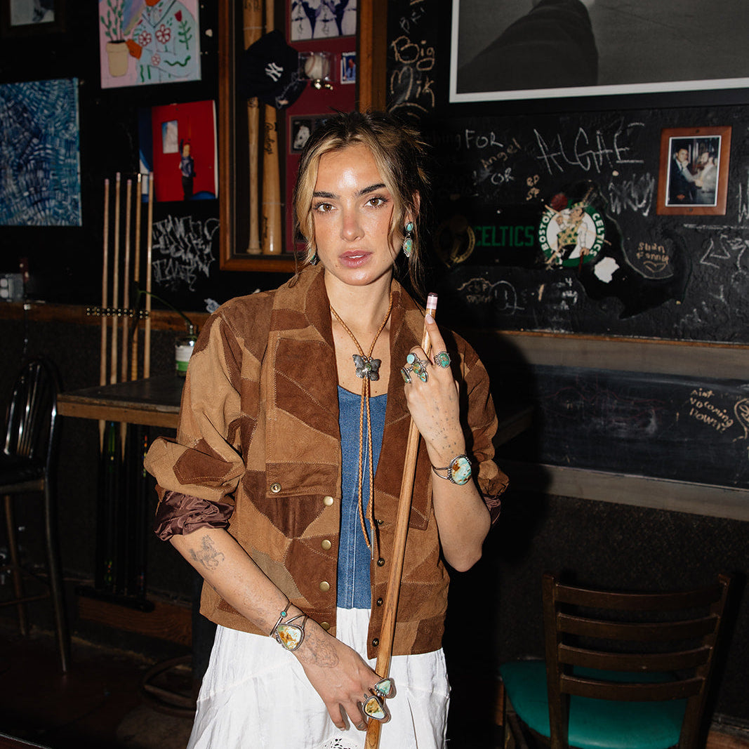 Woman standing in a bar with pool cues and a chalkboard wall.