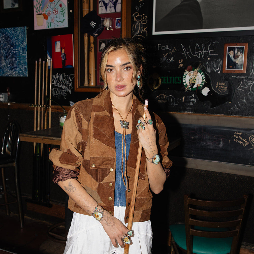 Woman standing in a bar with pool cues and a chalkboard wall.