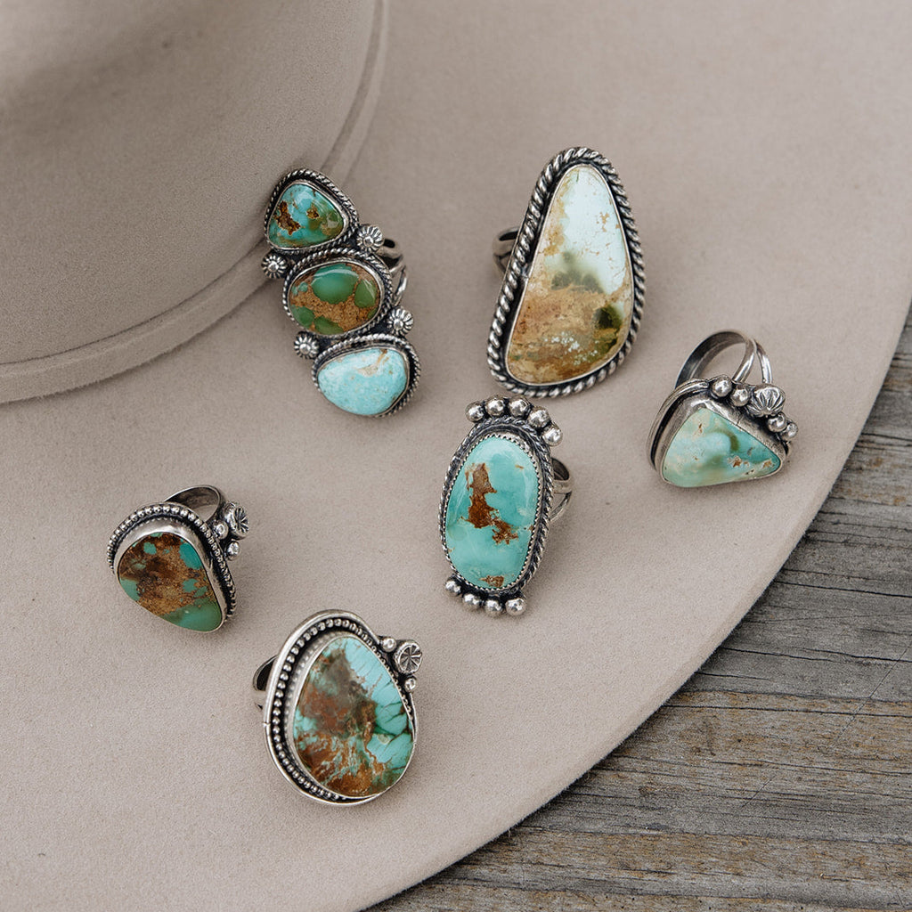 Set of turquoise stone rings with silver bands on a beige hat