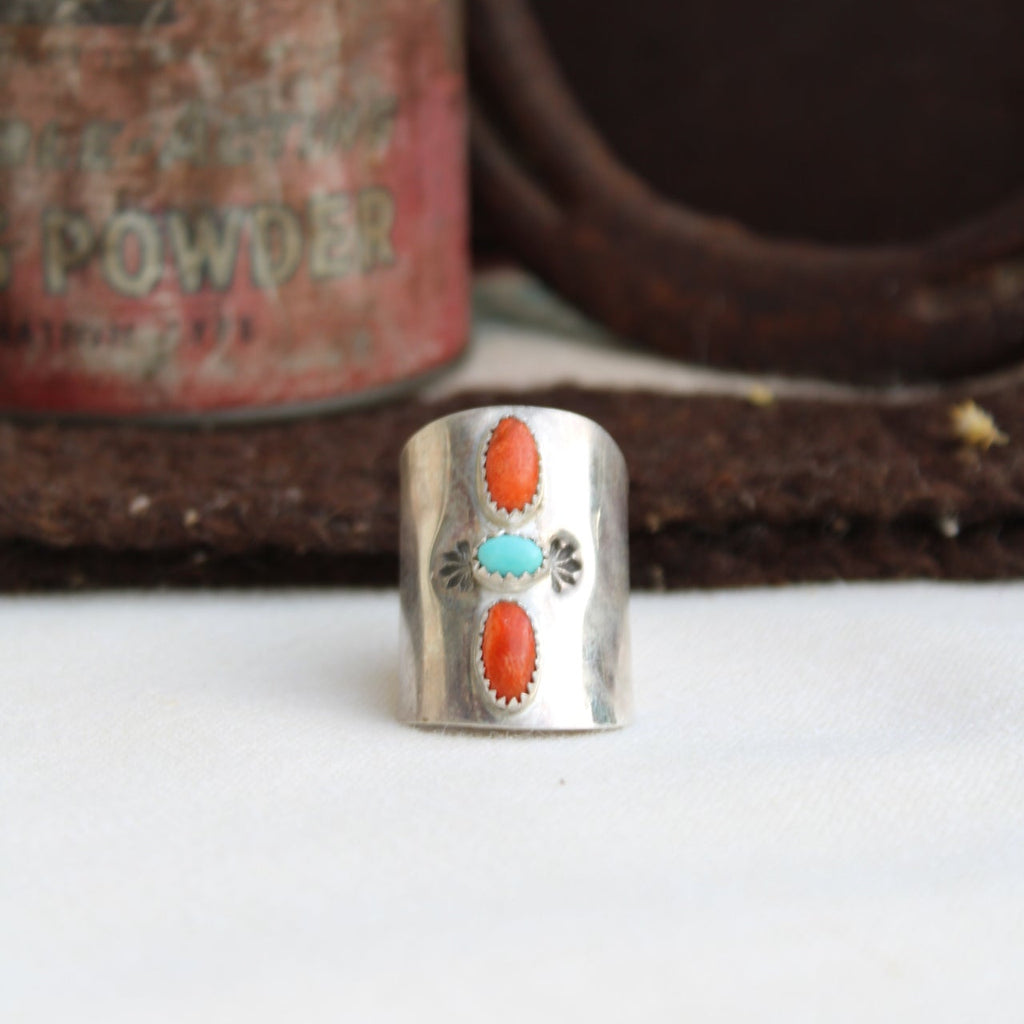 Silver ring with coral and turquoise stones on a textured surface