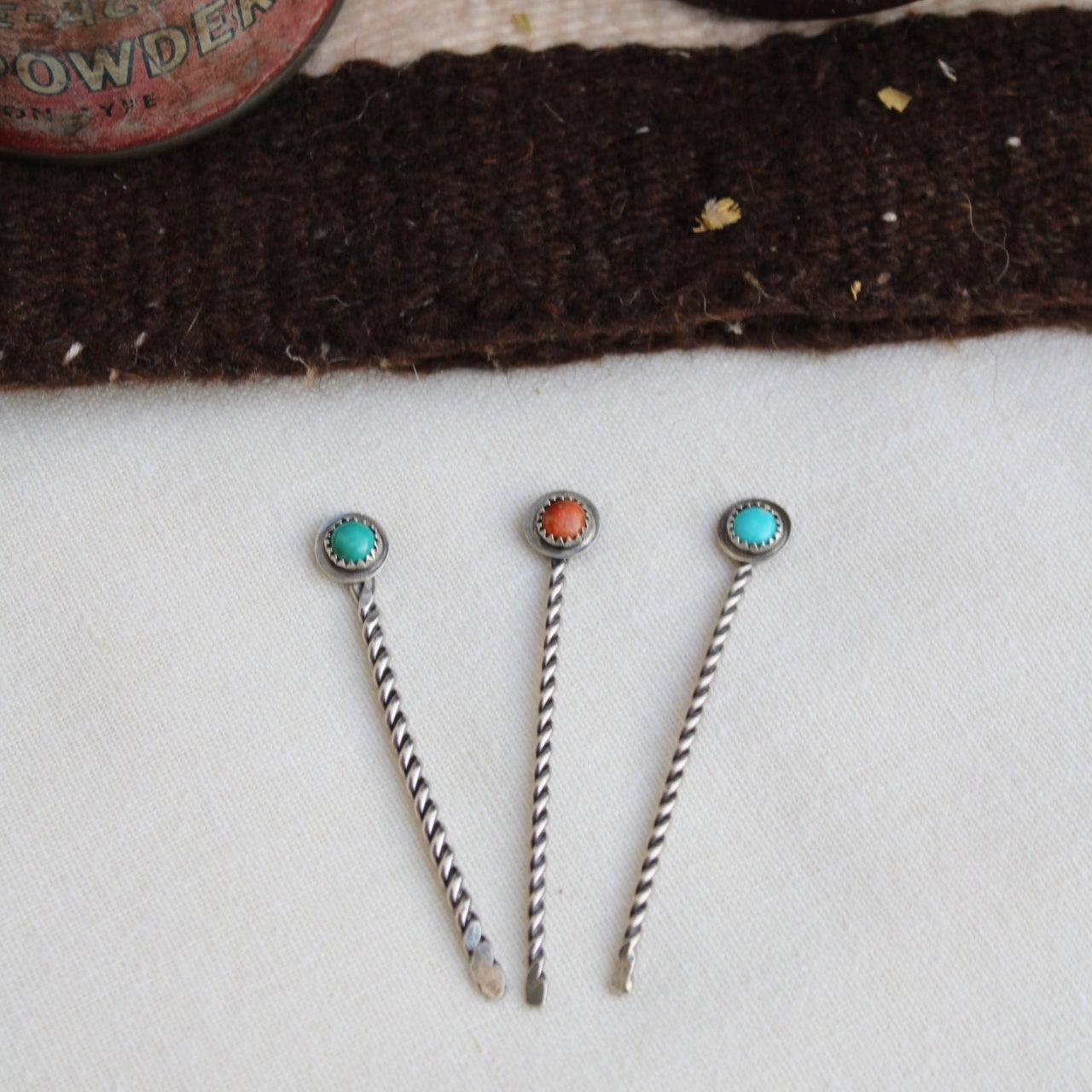 Three silver hairpins with gemstones on a textured surface