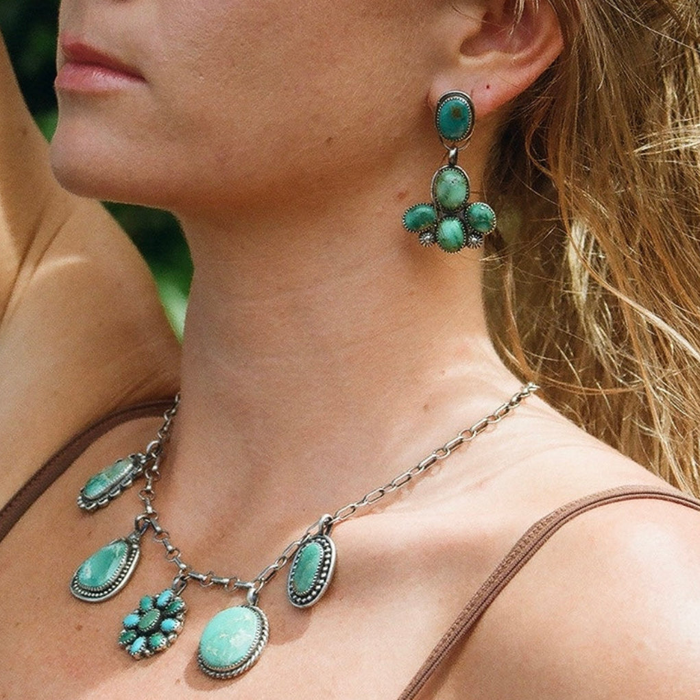 Woman wearing turquoise earrings and necklace with a blurred natural background