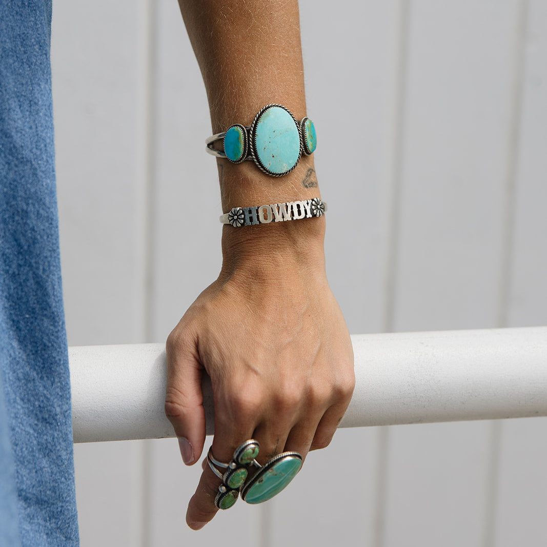 Person wearing turquoise rings on a white background
