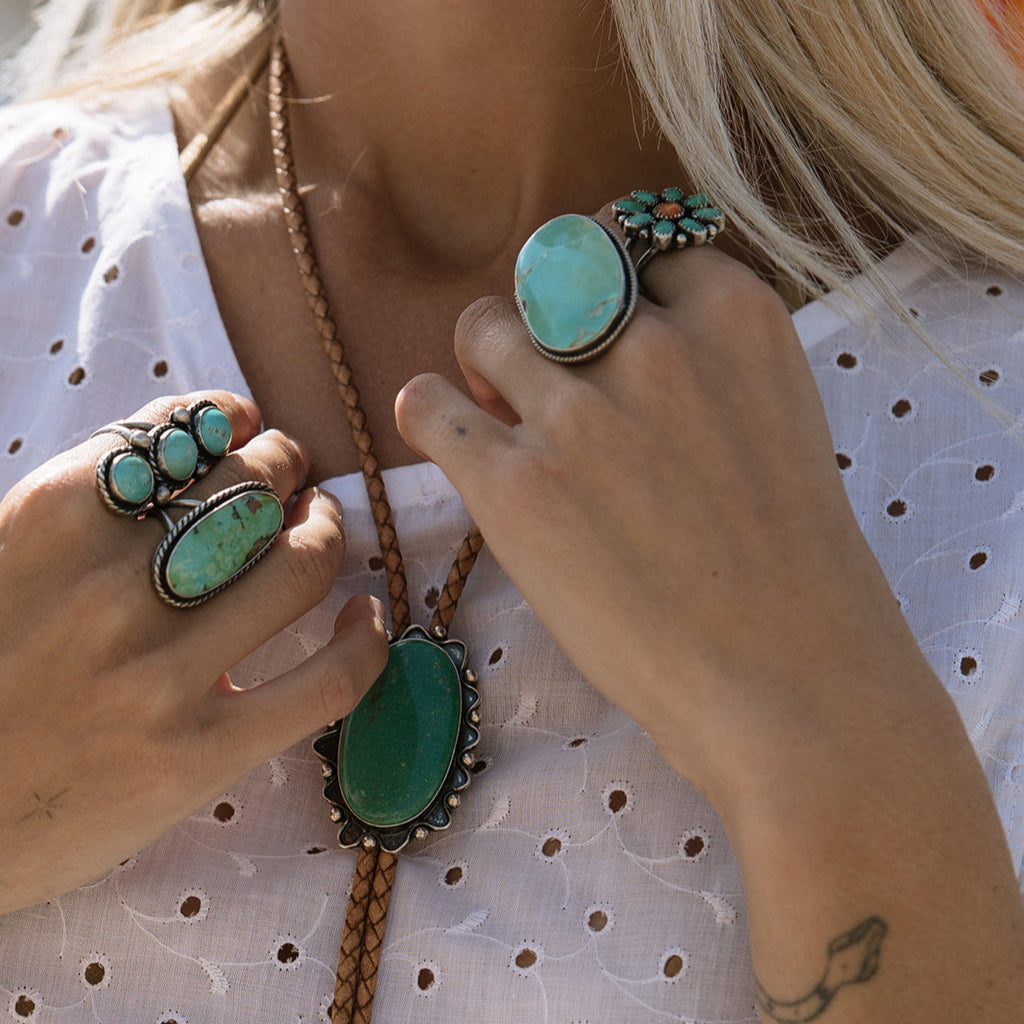 Close-up of turquoise jewelry on a person wearing a white polka dot top.